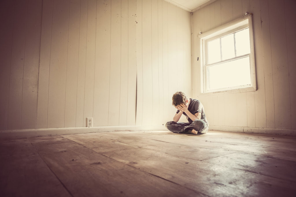Sad boy alone in a bare room